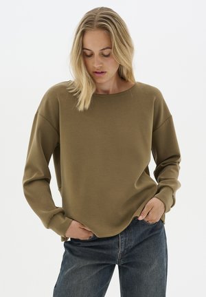 Khaki bluza z długimi rękawami, prążkowane mankiety i okrągły dekolt, w zestawieniu z ciemnoniebieskimi dżinsami. Gładka tekstura materiału.