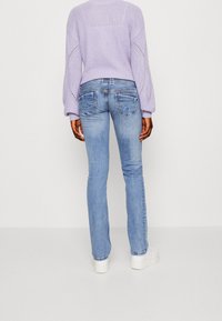 Ljusblå jeans med slim fit och lätt blekning, tillsammans med en lavendelfärgad stickad tröja med en texturerad design och öppna stygn.