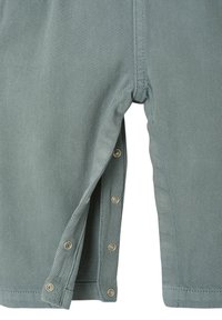 Kurze Hosen aus strukturiertem, hellgrünem Stoff mit seitlichem Druckknopfverschluss. Besitzen einen geraden Beinschnitt und sichtbare Nähte.