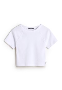 Camiseta blanca corta hecha de tela acanalada, con cuello redondo, mangas cortas estilo raglán y una pequeña etiqueta de la marca en el costado.