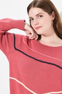 Różowy sweter dzianinowy z szerokim dekoltem, ozdobiony poziomymi paskami w kolorze granatowym i kremowym, z prążkowanymi mankietami oraz teksturowanymi detalami dzianiny.