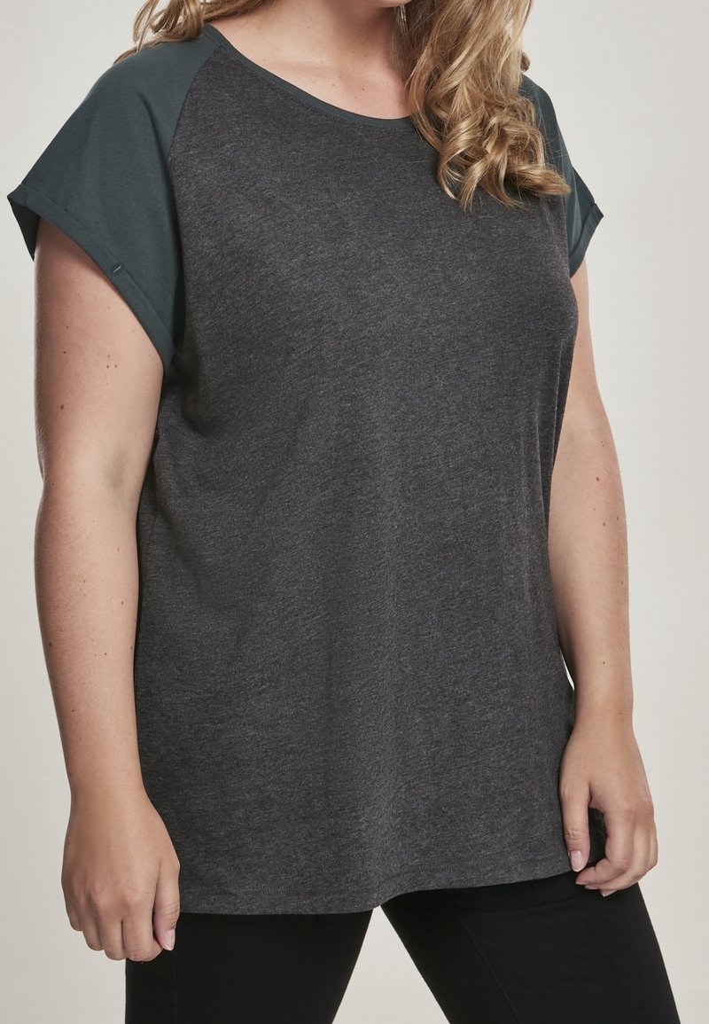 Top de manga corta gris oscuro con un diseño de hombro verde en contraste, hecho de tela suave, que presenta un ajuste relajado y un escote redondeado.