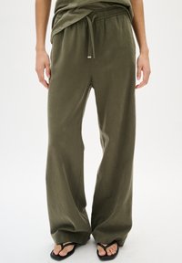 Olijfgroene wijde broek gemaakt van zachte stof, met een elastische tailleband en een trekkoord, en een ontspannen pasvorm voor comfort.