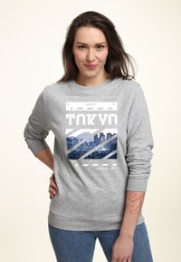 Felpa grigia con stampa grafica di uno skyline cittadino con il testo "TOKYO" e "CAPITAL CITY". Cuffie e vita a costine, vestibilità casual.