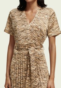 Omslagkjole lavet af letvægtsstof, med et beige og brunt zebra print, korte ærmer og en knyttet talje. Plisseret skørtedetalje.