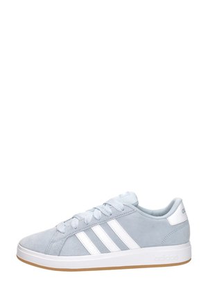 Hellgrauer Adidas-Turnschuh mit weißen Streifen, weißer Sohle und gummierter Außensohle, seitlich auf weißem Hintergrund gezeigt.