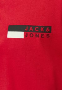 Rode katoen t-shirt met een zwart rechthoekig grafisch ontwerp met "JACK&JONES" in vette letters en een witte accentrechthoek.