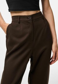 Bruine satijnen wijde broek met een flat front, ritssluiting en een enkele knoopsluiting. Zijzakken en een getailleerde pasvorm.