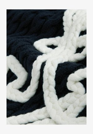 Marineblaue und weiße, gestrickte Decke mit einem dicken, geflochtenen Muster aus weichem, strukturiertem Garn. Das Design hebt kontrastreiche Farben und Texturen hervor.