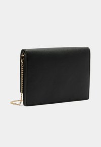 Clutch in finta pelle nera traforata con design a pieghe, dotato di una tracolla in catena dorata e una cucitura sottile lungo i bordi.