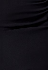 Sort stof med en glat, mat tekstur, der har rynkede detaljer langs den øverste sektion og en ren, ensfarvet nederste kant.