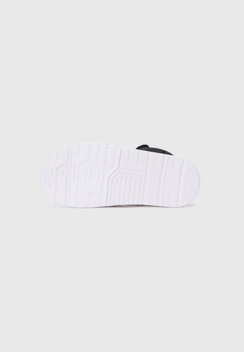 Zwarte sneaker met een gestructureerde bovenkant, voorzien van een witte rubberen zool. De zool heeft geribbelde patronen voor grip en tractie.