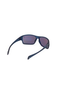 Sunglasses s tmavě modrým rámem, šedými skly, zakřiveným designem a tenkými nohami. Mají jemné logo na rámu.