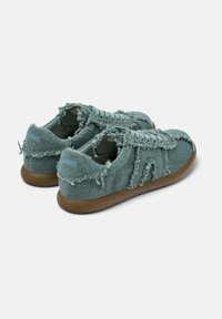 Green woven fabric sneakers with a frayed texture, lace-up design, and brown rubber soles. Rear displays small blue accent.
