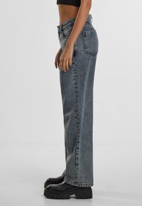 High-waisted, wide-leg jeans in distressed blue denim. Features classic five-pocket design, visible stitching, and a slight fade.