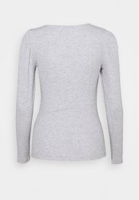 Grey long-sleeve top made of soft, textured fabric. Features a fitted shape and round neckline with slight gathering at the shoulders.