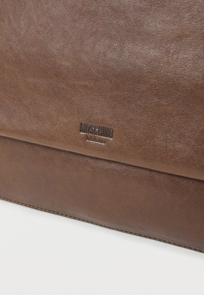 Καφέ δερμάτινη τσάντα Moschino Milano με υφή και εμφανές ανάγλυφο λογότυπο της μάρκας στην μπροστινή πόρπη.