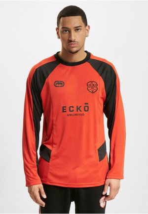 T-shirt de sport à manches longues en orange avec des accents noirs, doté d'un col rond et d'un logo placé sur la poitrine et les manches. Tissu doux et léger.