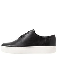 Zapatilla negra de cuero con un diseño aerodinámico, suela blanca plana y un detalle minimalista de cordones. Textura lisa con sutiles acentos de marca.