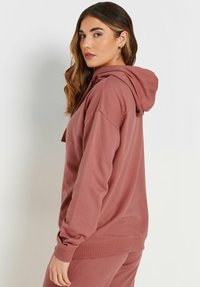 Felpa bordeaux realizzata in morbido tessuto, con cappuccio regolabile, vestibilità comoda e polsini e orlo a coste.