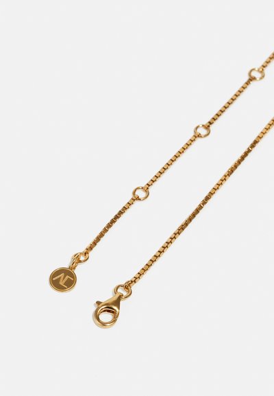 Gold chain necklace with a fine, delicate design. Features small circular links and a lobster clasp, accented by a circular logo tag.