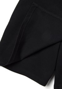 Gros plan sur un tissu noir plié montrant des coutures détaillées et une texture lisse sur le bord d'un vêtement.