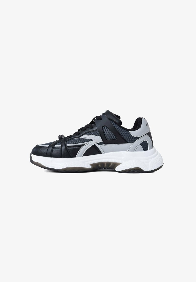 Baskets de sport noires et grises avec des panneaux en maille et en cuir, présentant une semelle blanche épaisse et des accents en caoutchouc noir contrastants.