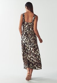 Maksi haljina s leopard printom od mekanog materijala, s niskim leđima, širokim trakama i lepršavim siluetom koja se proteže do gležnjeva.