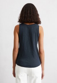 Marineblaue, ärmellose Tanktop aus weichem, leichtem Stoff. Rundhalsausschnitt und leicht abgerundeter Saum mit subtiler Textur.