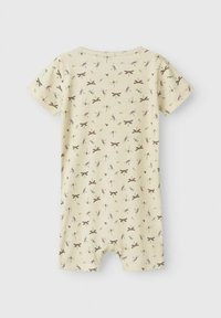 Combinaison à manches courtes en jaune clair avec un motif de libellule en marron et en teal. Tissu doux et extensible avec des ouvertures pour les jambes pour un enfilage facile.