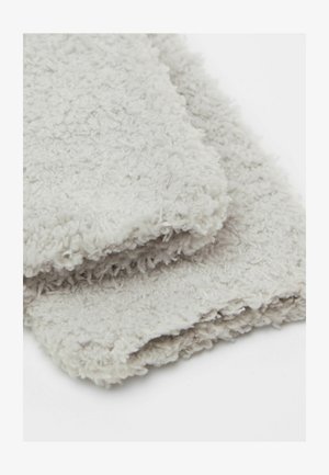 Světle šedá plyšová látka s měkkým, texturovaným povrchem. Dva složené kusy naskládané na sobě, s mírně třepenými okraji, což vytváří ležérní vzhled.