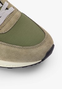 Zelené semišové tenisky s texturovaným povrchem, které mají hladký olivově zelený panel, šedé šňůrky a gumovou podrážku s černými akcenty.