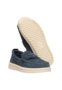 Zapatos de ante azul marino tipo mocasín, con suela texturizada de color crema y costuras decorativas a lo largo de la parte superior.