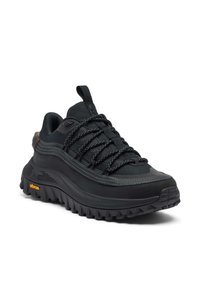 Musta urheilukenkä, jossa on teksturoitu kangaspäällinen, paksu kumipohja ja kuvioitu pito. Kenkässä on mustat nauhat ja keltainen Vibram-logo.