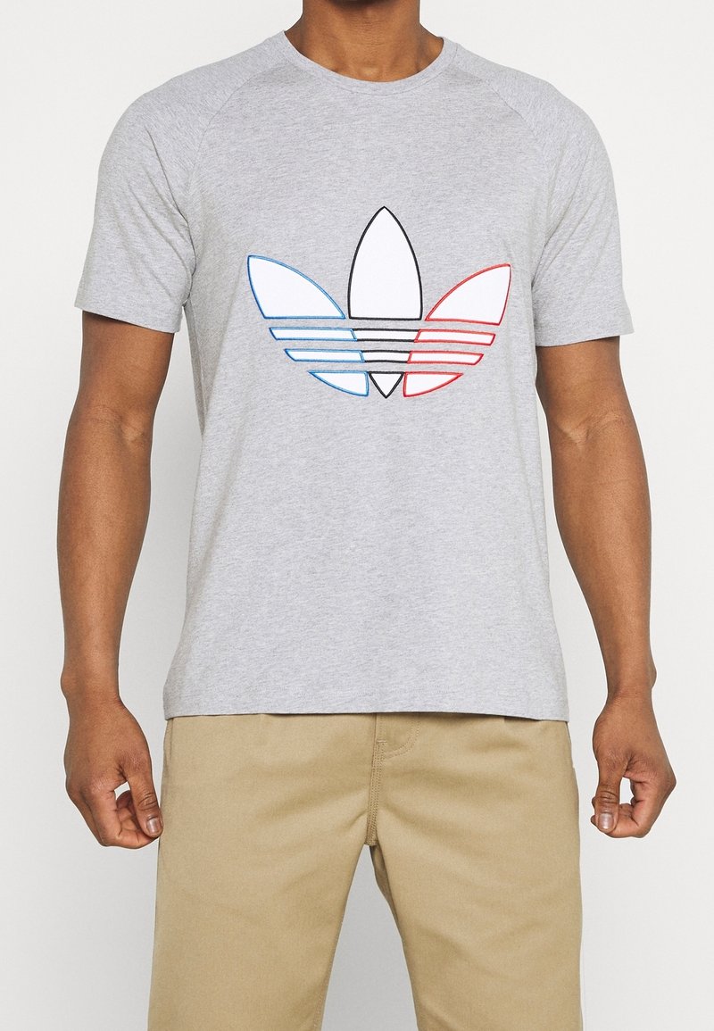 Grå kortärmad t-shirt med en stor flerfärgad Adidas trefoil-logotyp i blått, rött och svart kontur framtill.