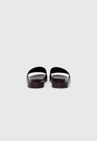 Black sandals with a minimalist design, featuring an open toe, wide straps, smooth texture, and flat soles for comfort.