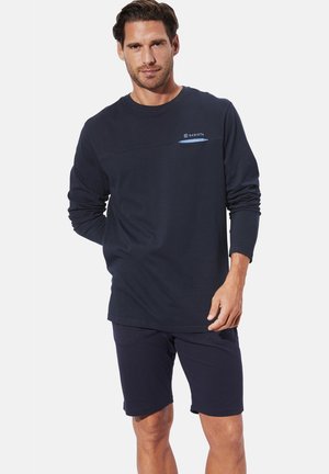 Navyblaues Langarmshirt mit einer horizontalen Brustnaht und hellblauen Akzenten, kombiniert mit dunklen Shorts, mit einem lässigen Schnitt und weicher Textur.