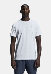 White athletic t-shirt made of lightweight fabric with a round neckline and short sleeves, featuring a subtle brand logo on the chest.