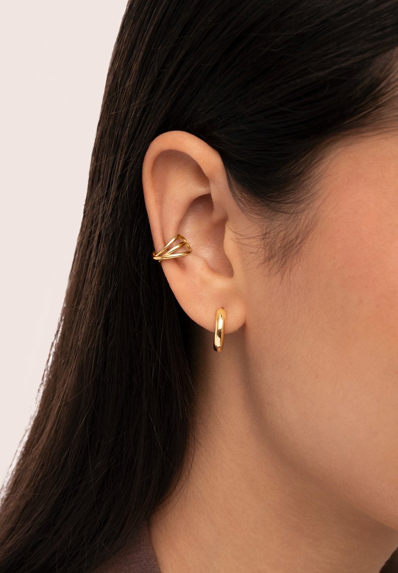 Gold-tone earrings featuring a sculptural design. One earring is a twisted shape, while the other is a smooth, rounded hoop.