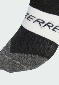 Μαύρη και γκρίζα κάλτσα με υφή. Διαθέτει λευκή ζώνη στην κορυφή με μαύρη εκτύπωση. Η μύτη είναι ενισχυμένη και κομμένη.