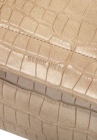 Beige leren tas met krokodillenpatroon, voorzien van een geperst "GERRY WEBER" logo en een gladde textuur, met een gestructureerde vorm en nette stiksels.