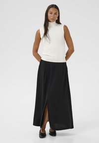 Hvid ærmeløs turtleneck top parret med en sort maxi nederdel med en frontslids; glat tekstur, enkelt design og afslappet pasform.