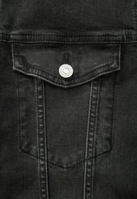 Schwarze Denim-Weste mit einer Fronttasche, silberner Druckknopfschließe und genähten Details entlang der Kanten. Weiche Textur und taillierte Form.