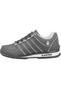 Grauer Sportschuh mit einer strukturierten Synthetik-Oberfläche, sechs weißen Schnürsenkeln, drei weißen Streifen und einer schwarzen Gummisohle. Logo auf der Ferse.
