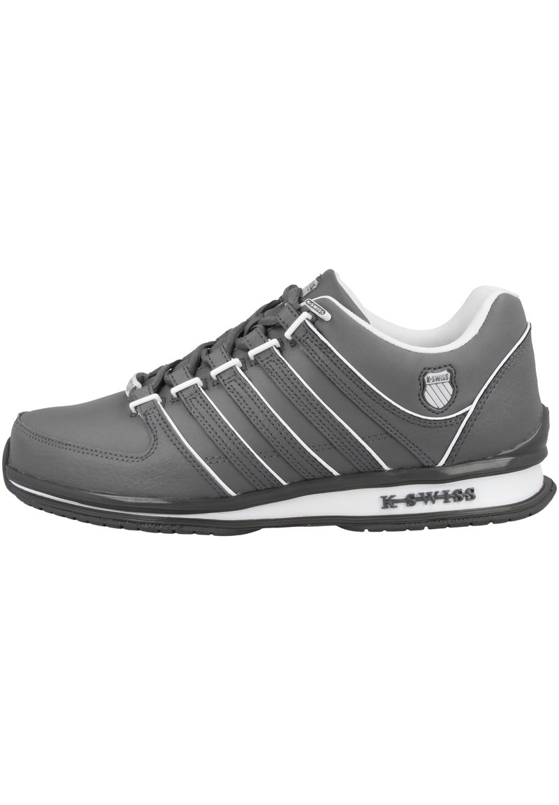 Grauer Sportschuh mit einer strukturierten Synthetik-Oberfläche, sechs weißen Schnürsenkeln, drei weißen Streifen und einer schwarzen Gummisohle. Logo auf der Ferse.