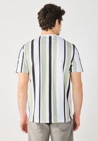 Camiseta de manga corta con rayas verticales en verde, blanco y negro. Tejido suave, corte holgado, escote redondo y diseño simple.