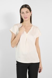 Cream-colored blouse with a V-neck and short, loose sleeves. Textured fabric with a softly draped silhouette. Plain design, no patterns.