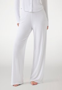 White, ribbed wide-leg pants made of soft fabric, featuring a relaxed fit and a smooth texture. Accentuated with minimal detailing.