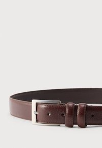 Καφέ δερμάτινη ζώνη με υφή, ασημένια τετράγωνη πόρπη και δύο δερμάτινους κρίκους σε λευκό φόντο.