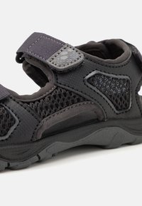 Sorte utendørs sandal i svart med mesh-paneler, justerbare stropper, teksturert såle og forsterket søm for holdbarhet. Lett vekt.